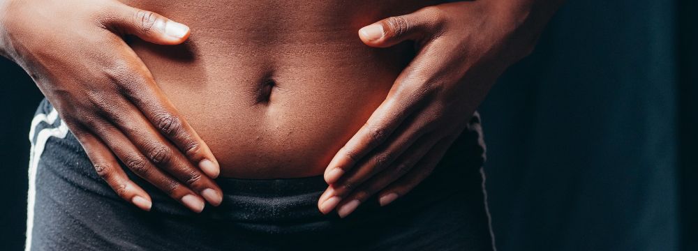 Woman placing both hands on stomach