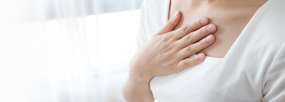 Woman experiencing GERD symptoms placing both hands covering chest area